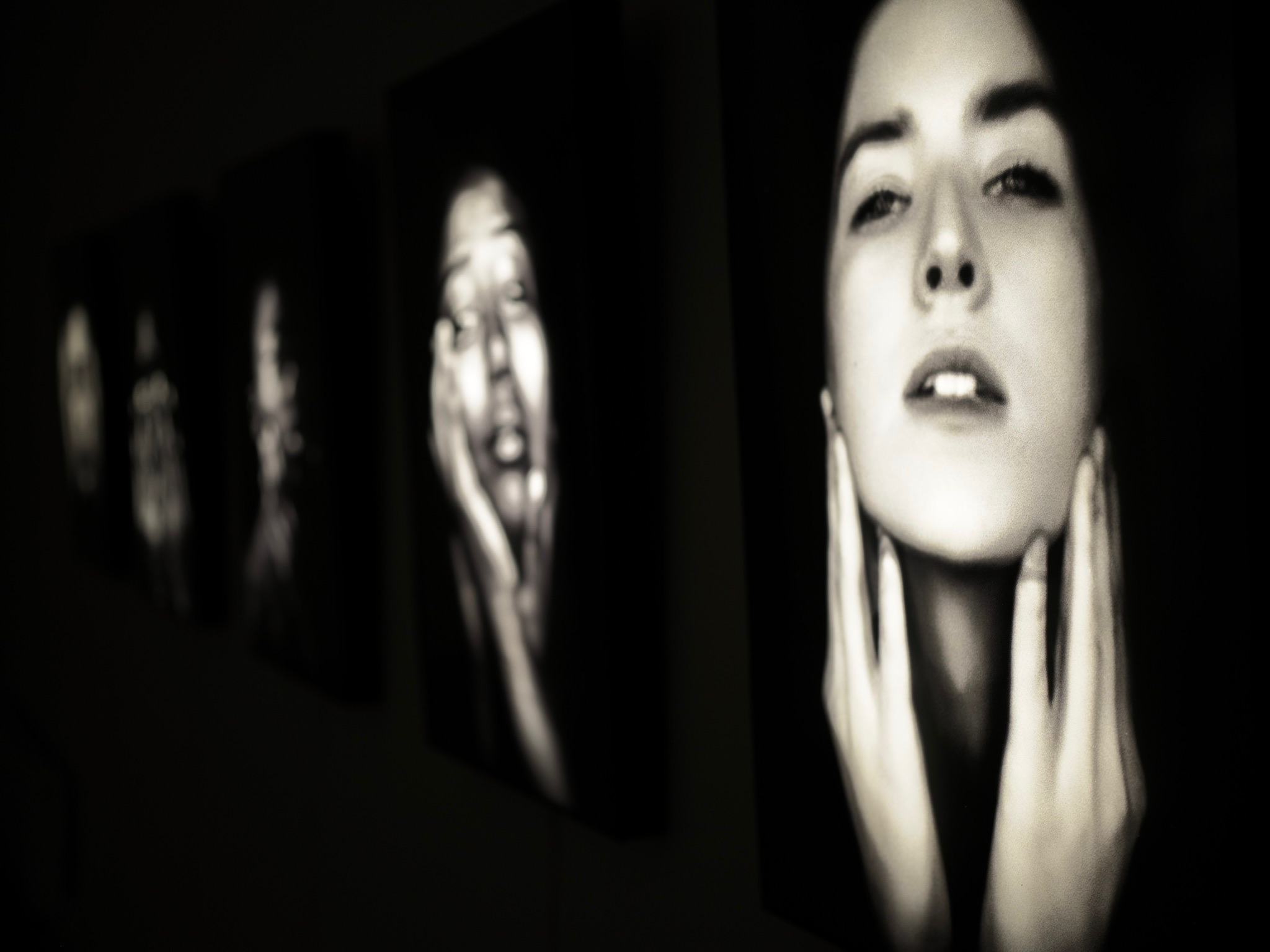 Installation view: a recession of lit portraits along the basement wall at Espace Thorigny, Paris
