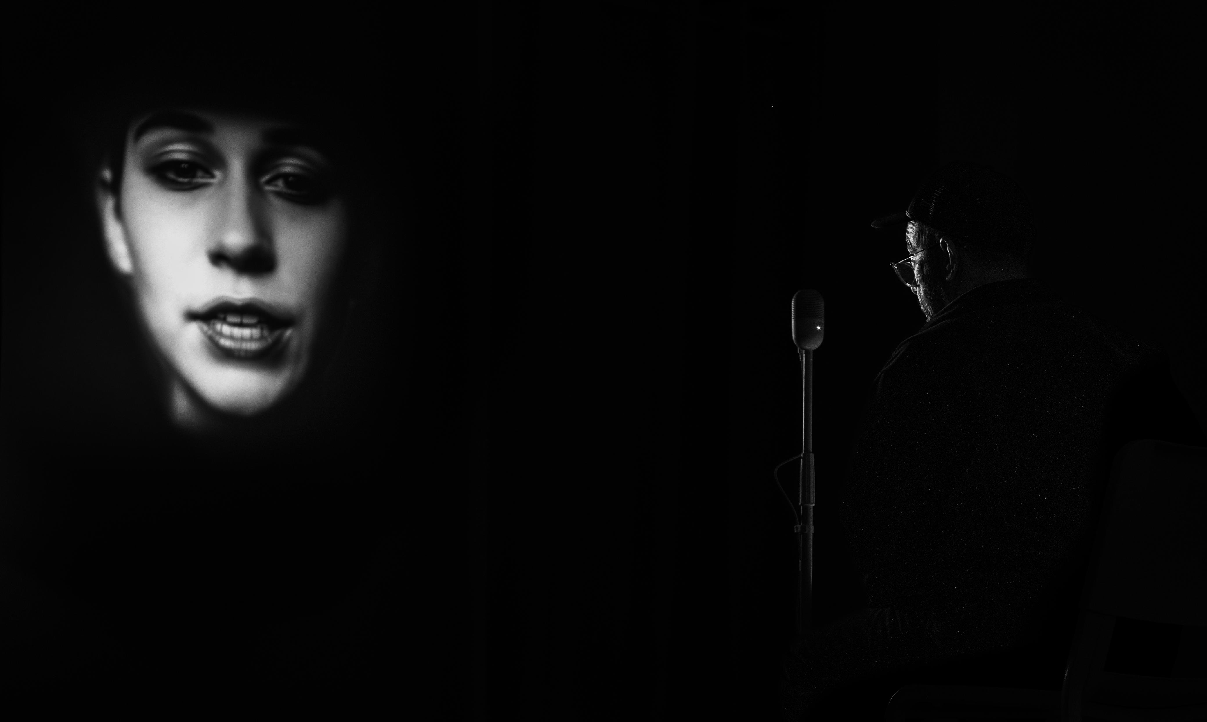 The chamber: SOLIENNE on screen at left, microphone centered, the performer seated at right in low light.